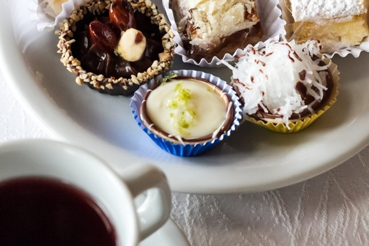 Mesa posta no salão da confeitaria, com doces e café